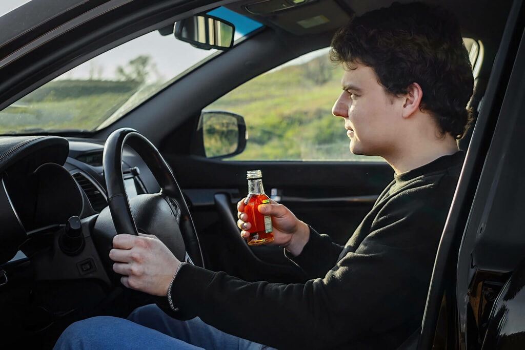 motorista cometendo uma multa gravíssima ao beber no volante
