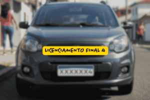Carro cinza com placa terminada em 4 estacionado em rua residencial, com a mensagem “Licenciamento final 4” centralizada sobre faixa amarela, alertando sobre prazos obrigatórios.