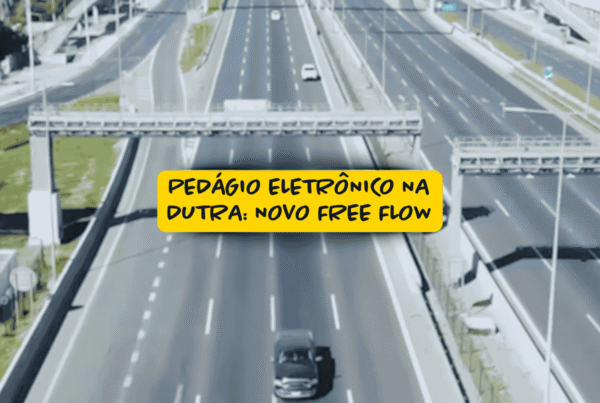 Vista aérea de rodovia com faixas largas e estruturas de pórticos eletrônicos para cobrança automática; destaque para a frase “Pedágio eletrônico na Dutra: novo free flow” em caixa amarela no centro da imagem.