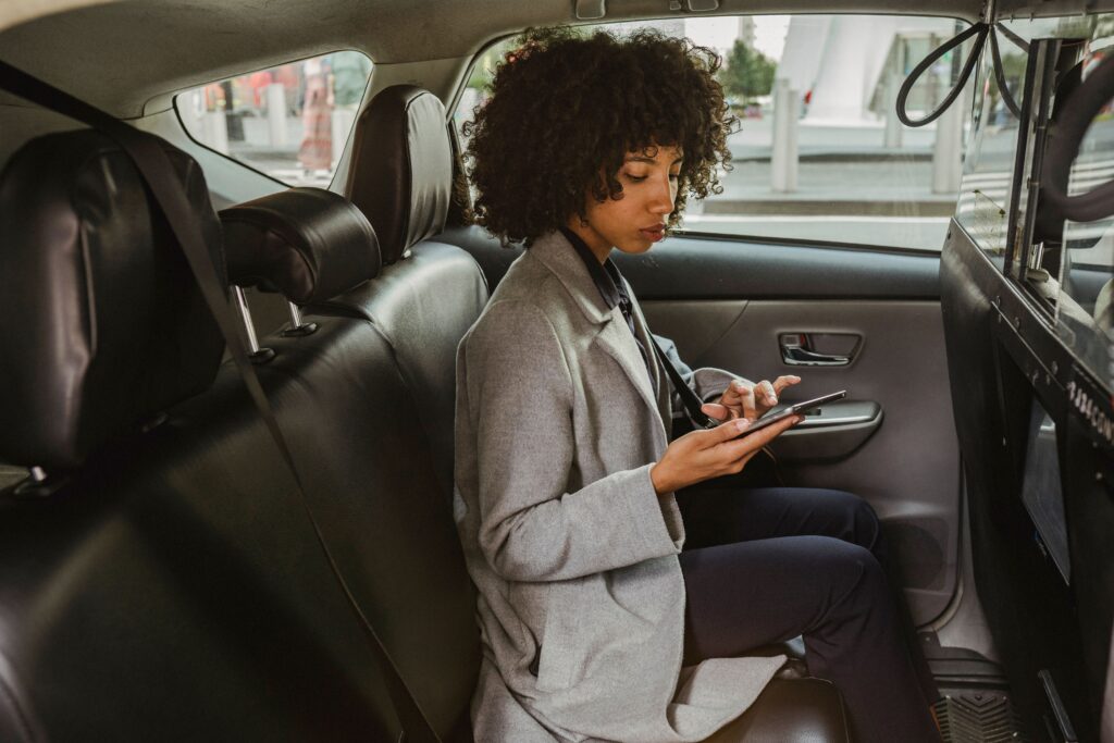 Mulher consultando informações pelo celular no banco de um automóvel