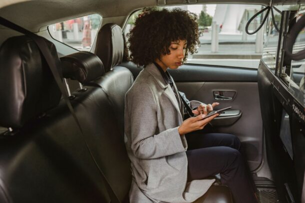 Mulher consultando informações pelo celular no banco de um automóvel