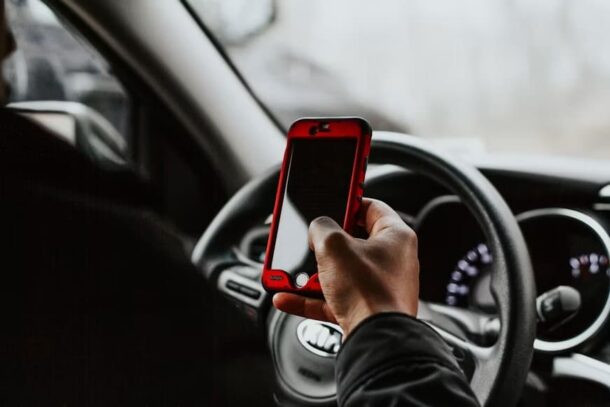 Pessoa acessa o documento digital do veículo pelo celular próximo ao volante.