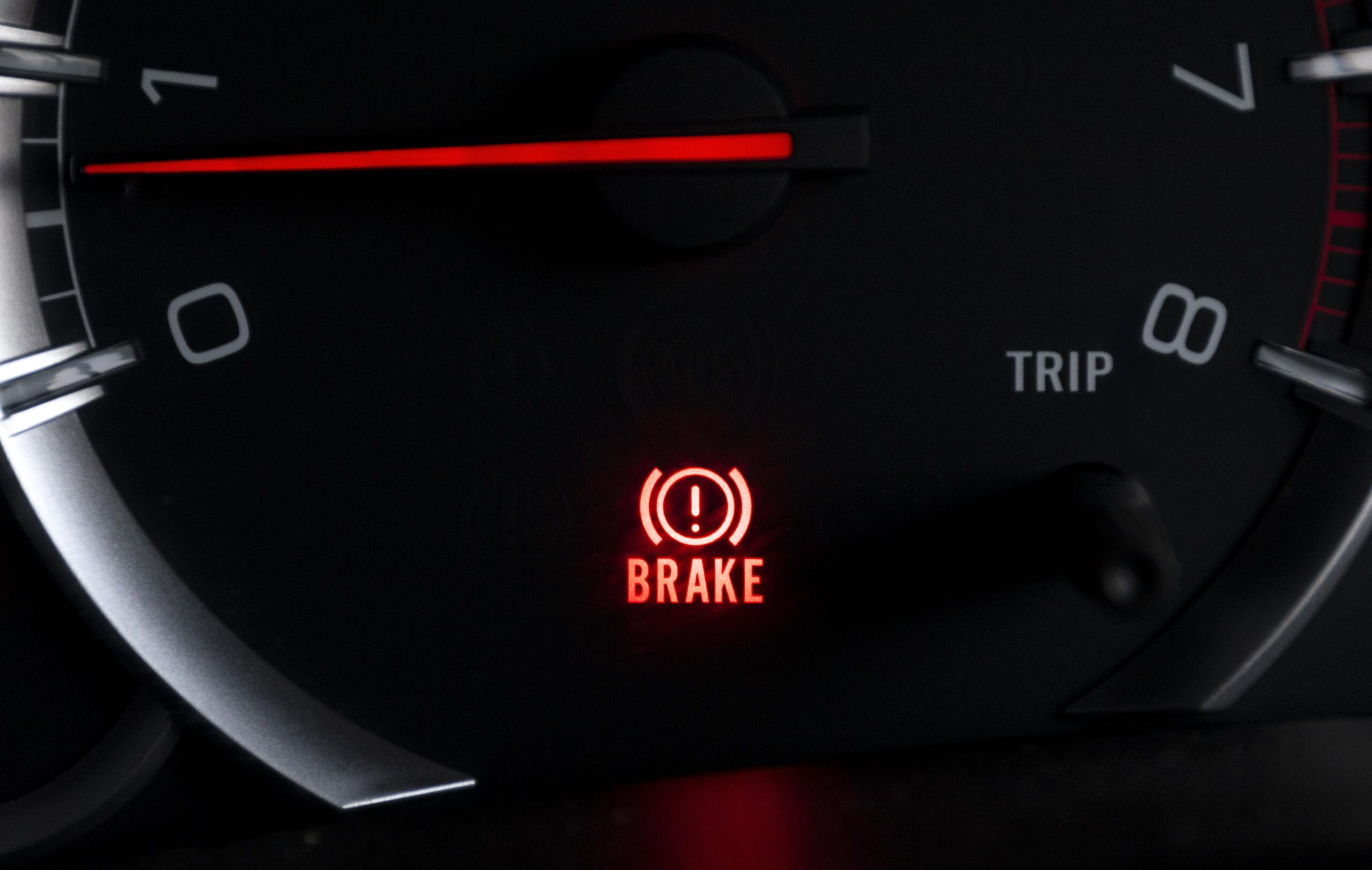 Luz vermelha de advertência do sistema de freios acesa no painel de um carro.