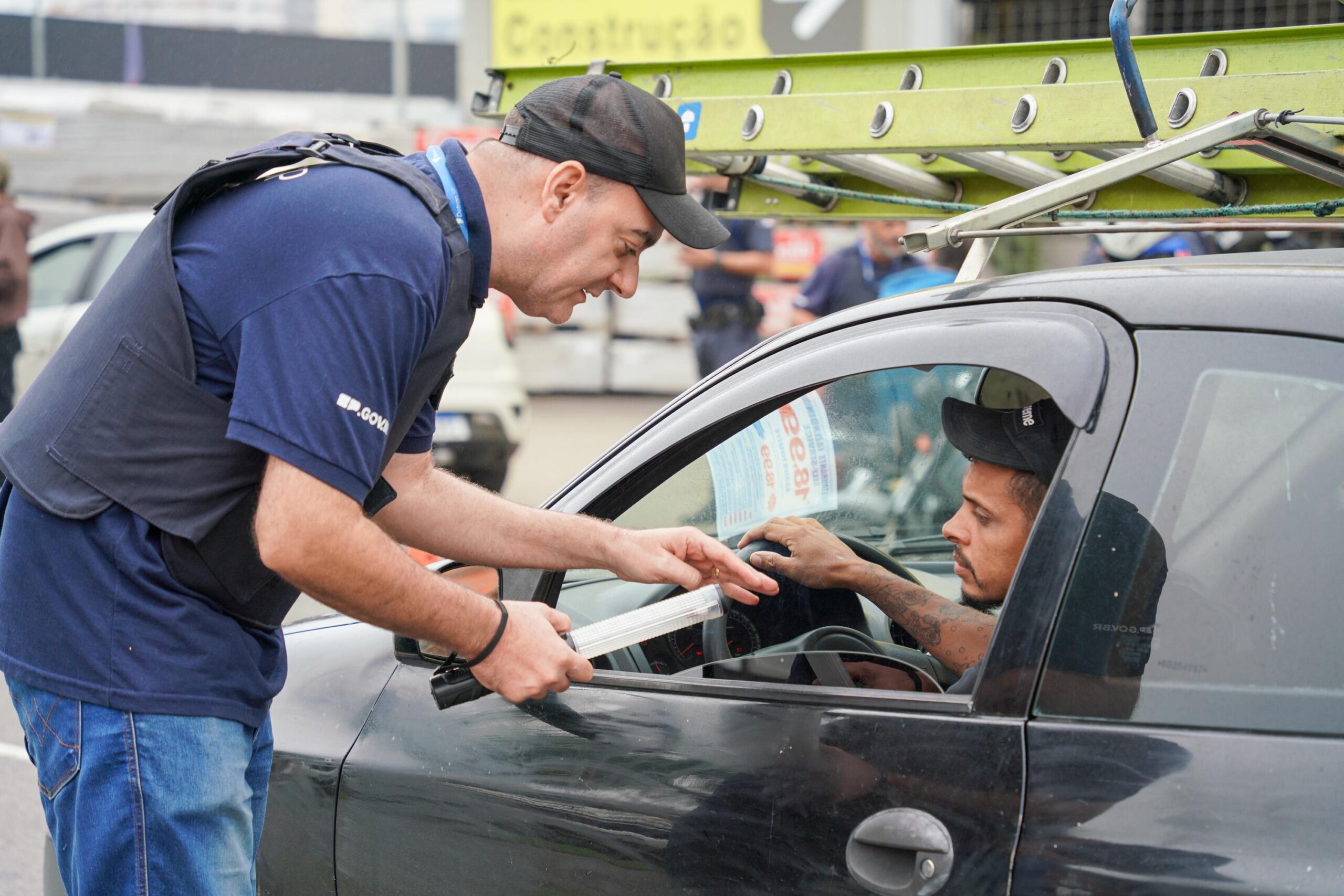 Agente de trânsito verifica os documentos de um motorista durante fiscalização, ilustrando a diferença entre não portar a CNH e dirigir sem habilitação.