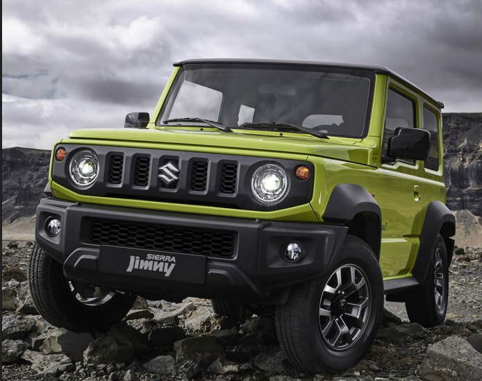 Suzuki Jimny Sierra verde em terreno de pedras, destacando o porte compacto e o estilo off-road.